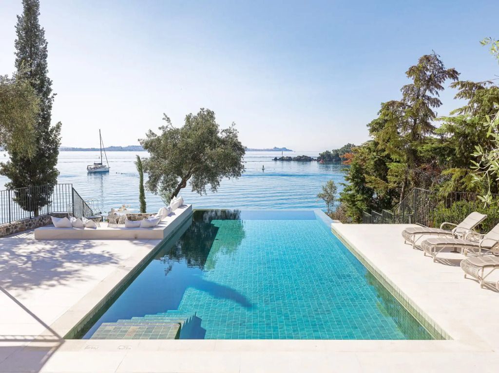 Infinity-Pool mit kristallklarem Wasser und Blick auf das Meer unter blauem Himmel.