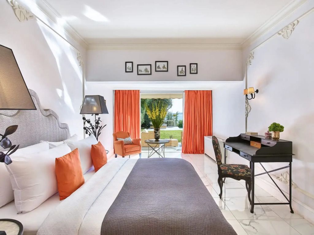 Elegantes Hotelzimmer mit stilvollen Möbeln und Blick auf den Garten durch große Fenster