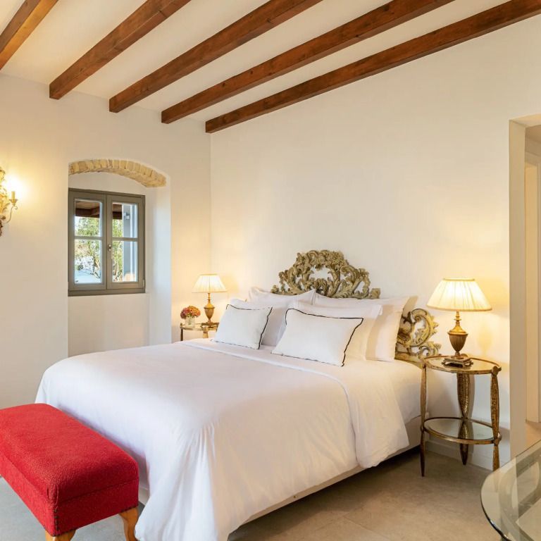 Komfortables Schlafzimmer mit eindrucksvollem Bettkopfteil und roter Sitzbank im Medusa Estate.