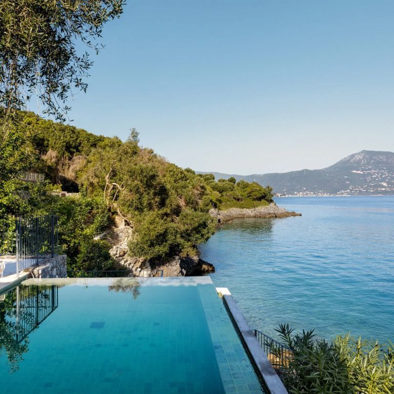 Infinity-Pool mit Blick auf das blaue Meer und grüne Hügellandschaft