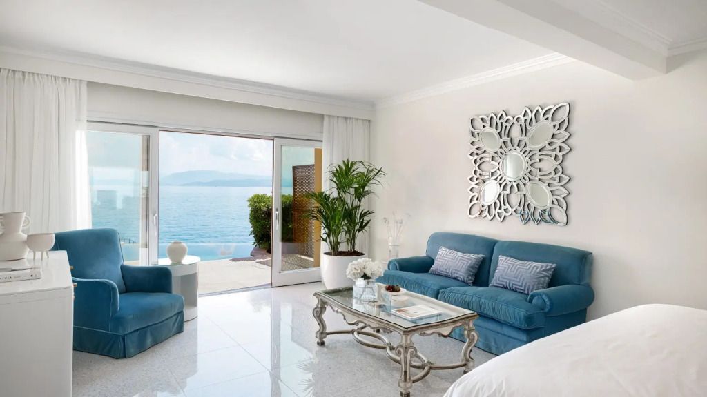 Helles Wohnzimmer mit blauen Sofas, Glas-Couchtisch und Meerblick.