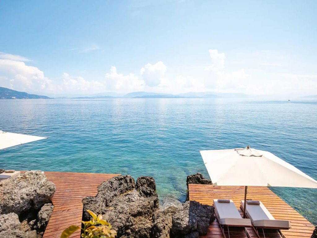 Blick auf das stille Meer von einer luxuriösen privaten Terrasse mit Sonnenliegen