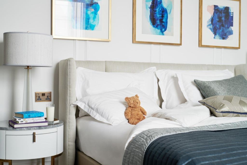 Plüschbär auf Bett im Familienzimmer des Corinthia London mit künstlerischen Akzenten
