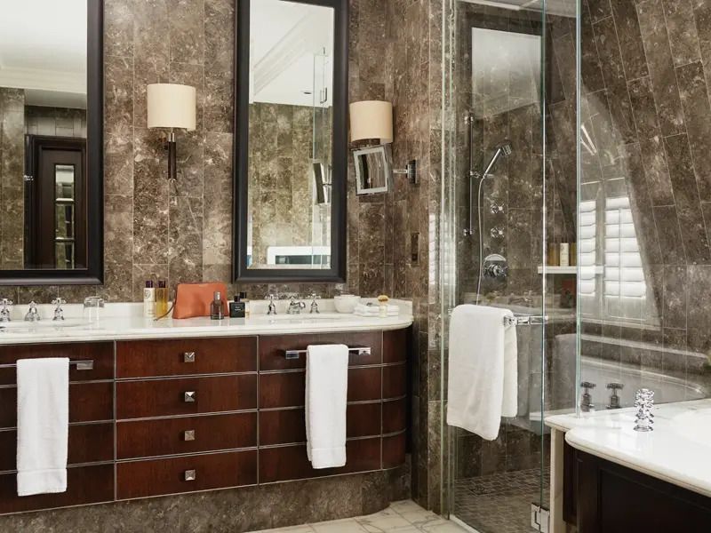 Luxuriöses Badezimmer in edlem Marmor mit großer Dusche und Doppelwaschbecken.