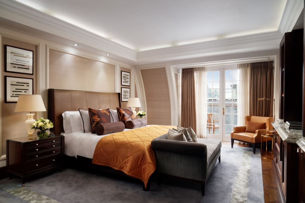 Luxuriöses Schlafzimmer mit Doppelbett und Zugang zu einem Balkon im Corinthia London
