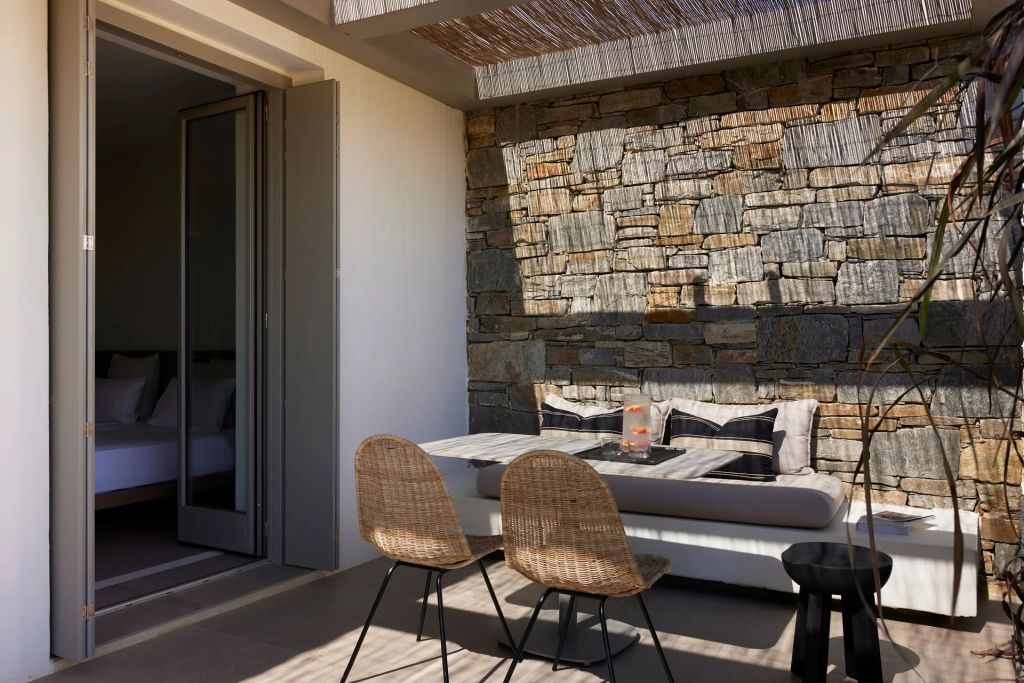 Gemütliche Terrasse mit Steinwand und komfortabler Sitzgelegenheit.
