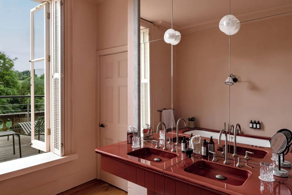 Badezimmer mit Doppelwaschbecken und stilvollem Spiegel in warmen Farben.
