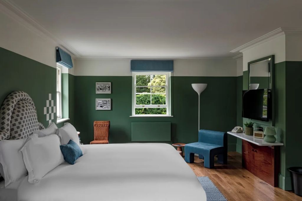 Junior Suite mit grün-weißer Wandgestaltung, Doppelbett und bequemen Sesseln