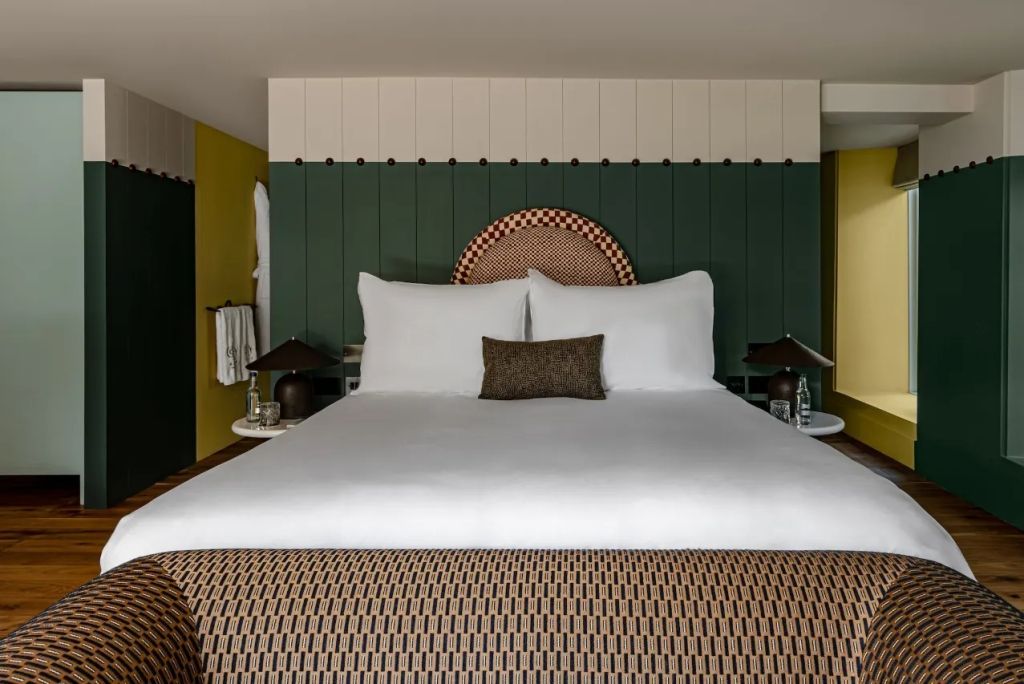Elegantes Doppelbett mit grüner Wand und stilvollen Nachttischen im Wildflower Zimmer