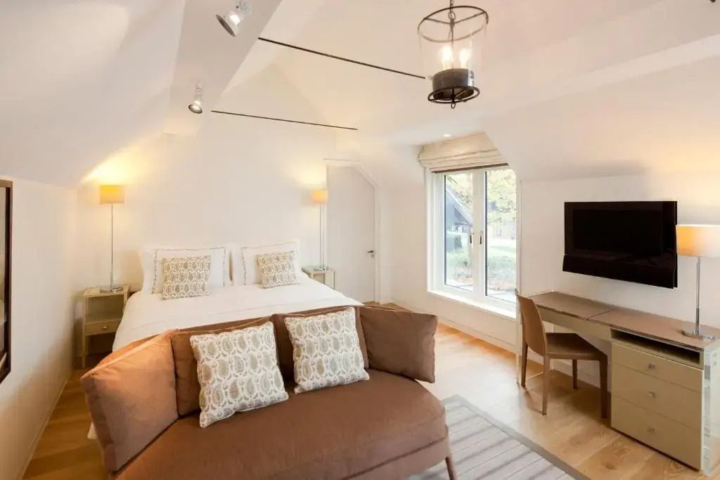 Moderne Einrichtung mit Doppelbett, Sitzecke und großem Fenster.
