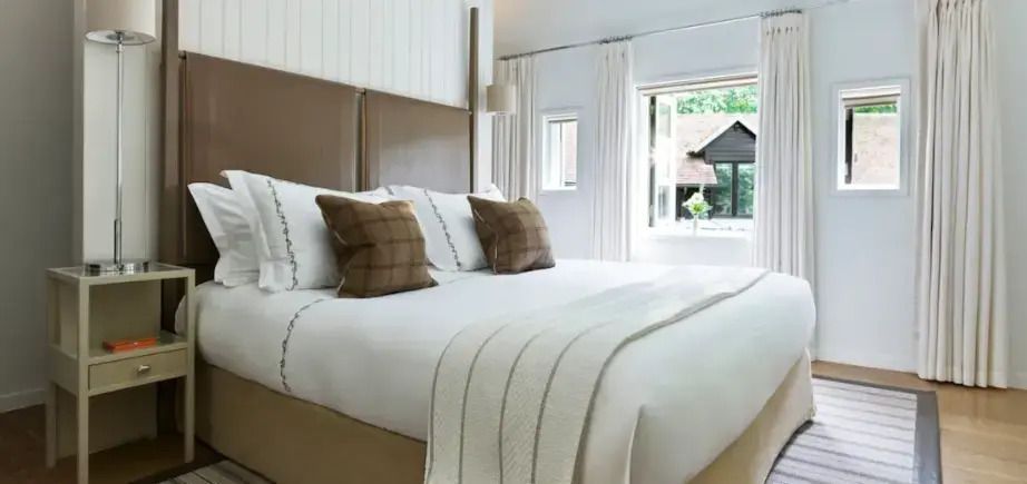 Helles Schlafzimmer mit großem Doppelbett und offenem Fenster mit Gartenblick