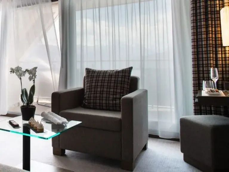 Komfortabler Sitzbereich mit Sessel und Glas-Couchtisch im hell beleuchteten Zimmer