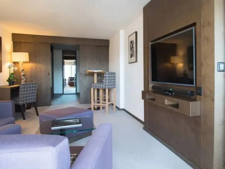 Moderne Wohnbereich der Prestige Suite mit komfortablen Sesseln und großem TV.