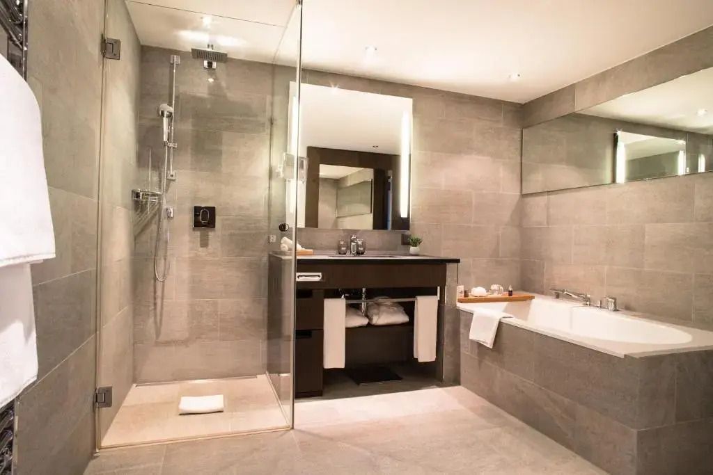 Luxuriöses Badezimmer mit Regendusche und großer Badewanne im Crans Ambassador.