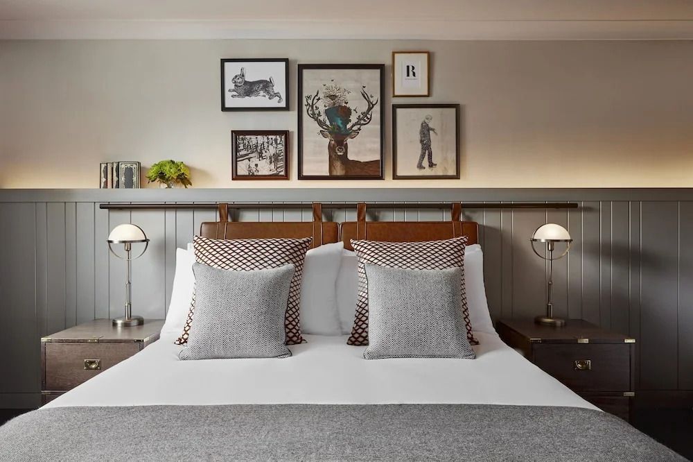 Doppelbett mit stilvollen Kissen und Kunstwerken an der Wand