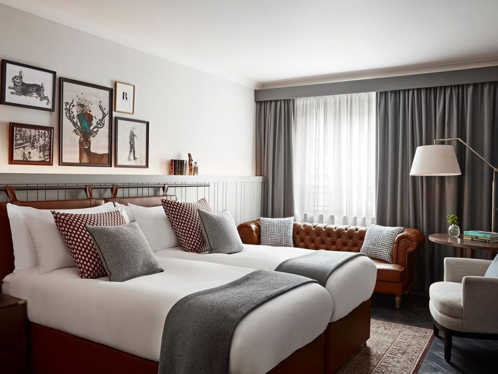Doppelzimmer mit zwei Betten, Ledersofa und stilvollen Dekokissen