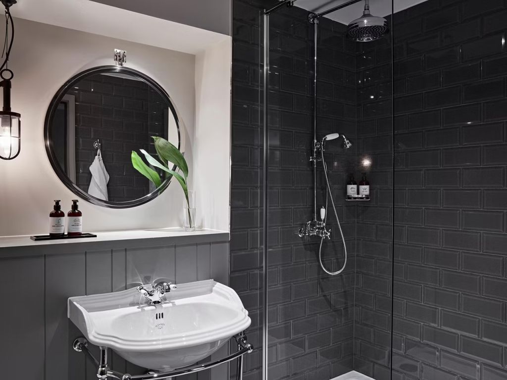 Modernes Badezimmer mit dunklen Fliesen und stilvoller Duschausstattung