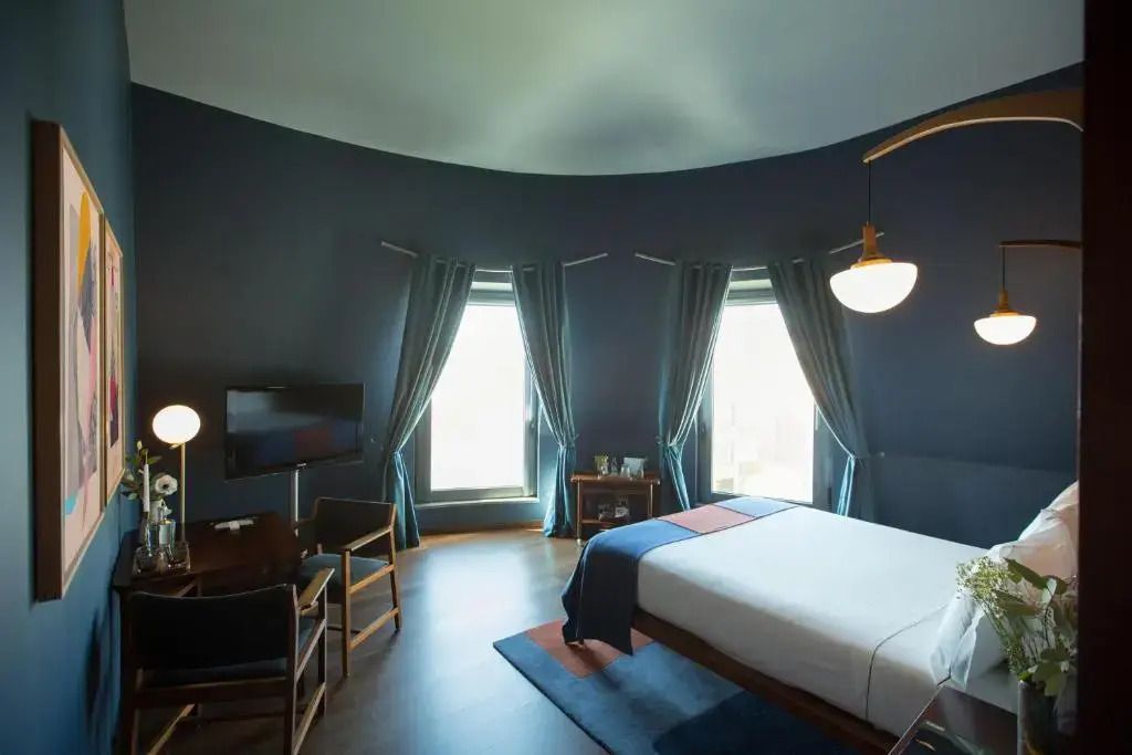Geräumige Suite mit großem Doppelbett und eleganten Vorhängen vor Panoramafenstern.