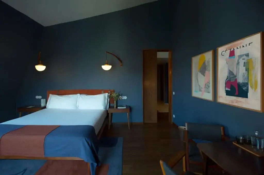 Luxuriöse Ecke der Suite mit modernem Doppelbett und stilvollen Kunstwerken an der Wand.