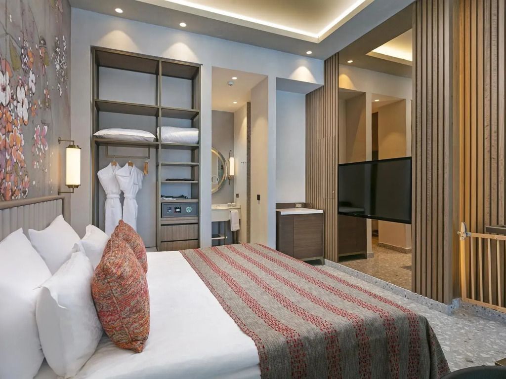Helles Familienzimmer mit Doppelbett. Moderne Einrichtung und Regale mit Bettwäsche.
