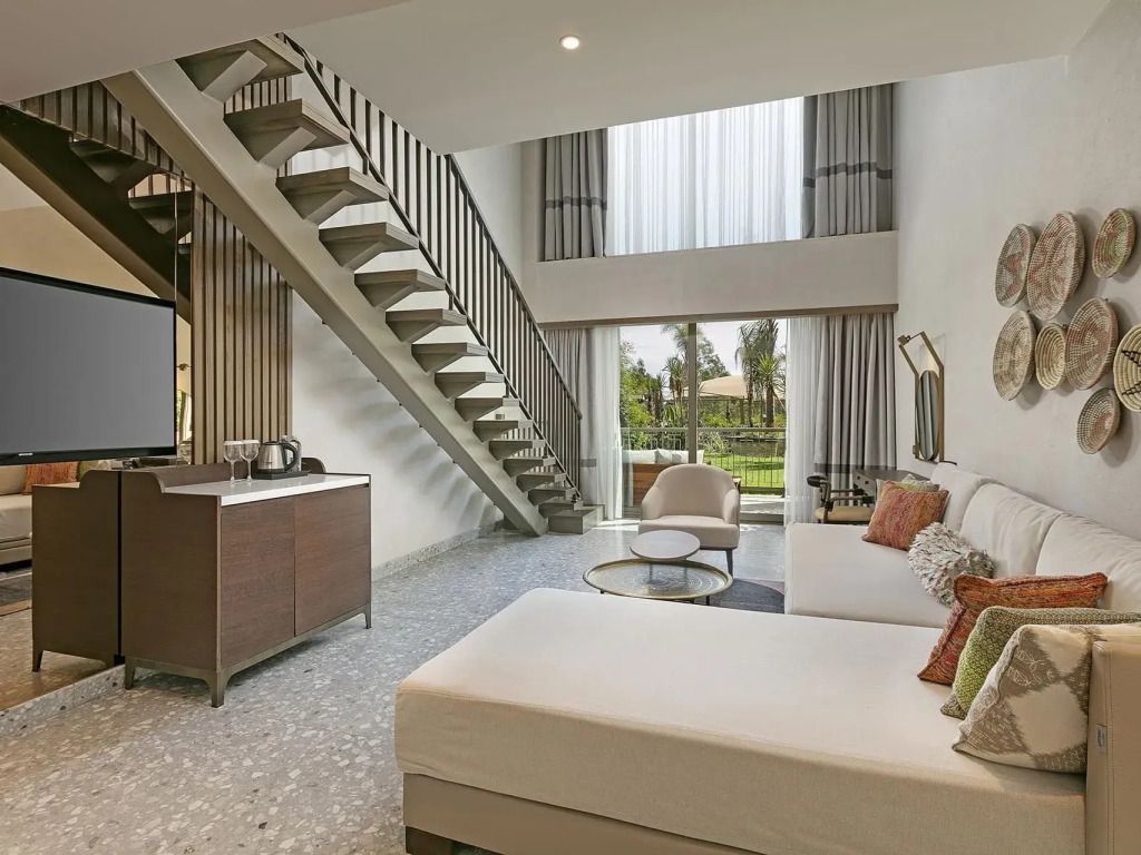 Duplex-Wohnbereich mit Treppe. Große Fenster mit Blick ins Grüne und eleganten Möbeln.