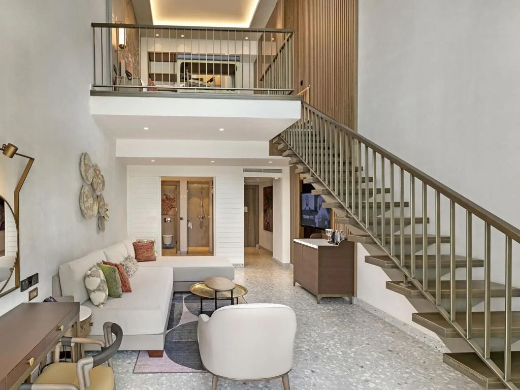 Duplex-Suite mit Treppe. Geräumiges Wohnzimmer mit modernen Möbeln und Kunst.