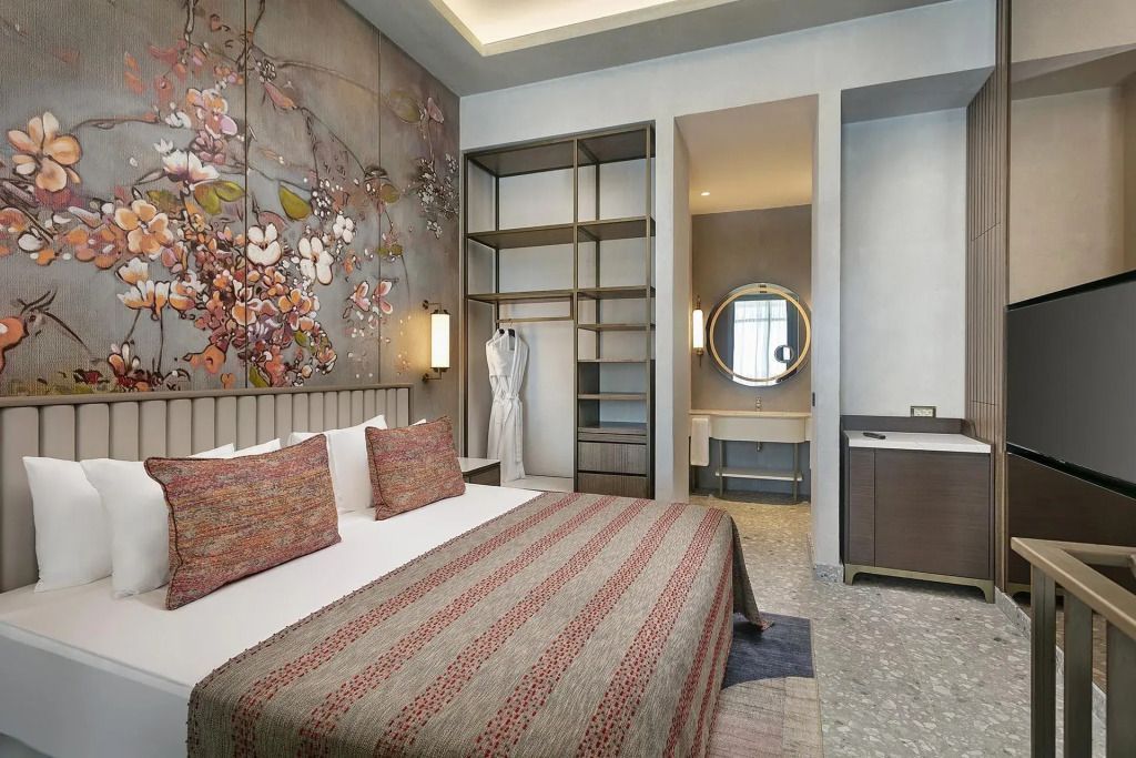 Eleganter Schlafbereich im Grand Swim-Up Zimmer mit dekorativen Kissen und Garderobe
