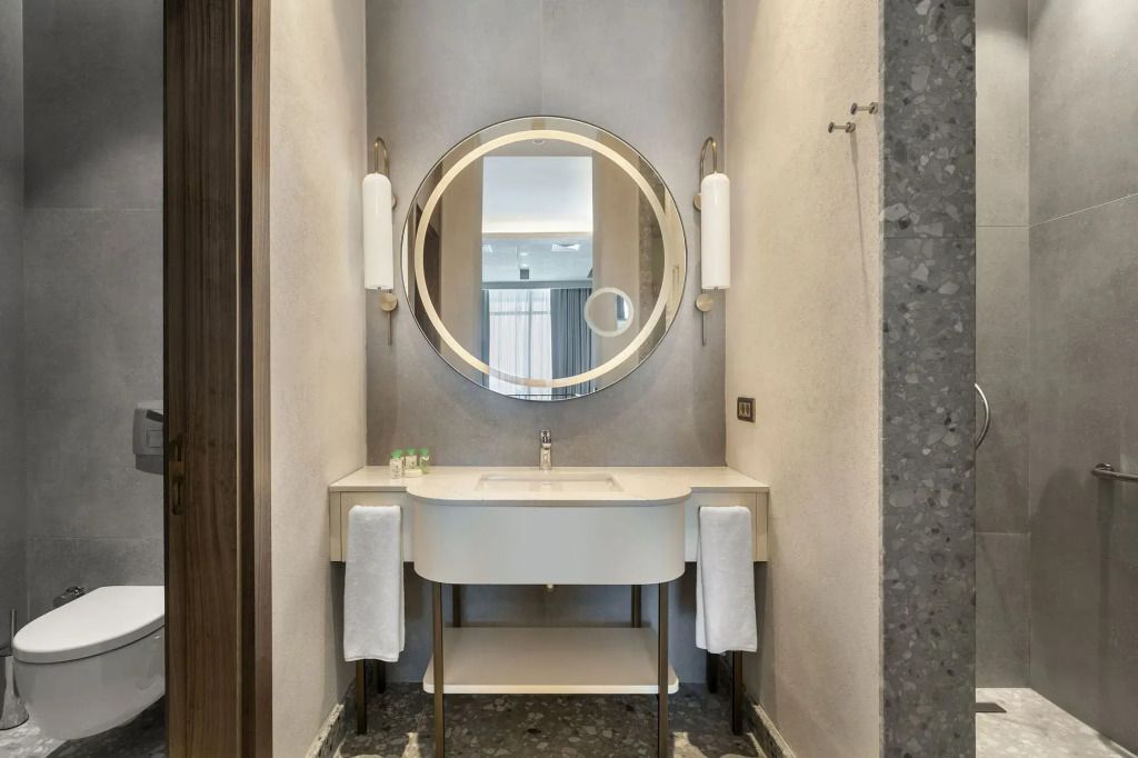 Luxuriöses Badezimmer mit rundem Spiegel und eleganter Waschtischarmatur