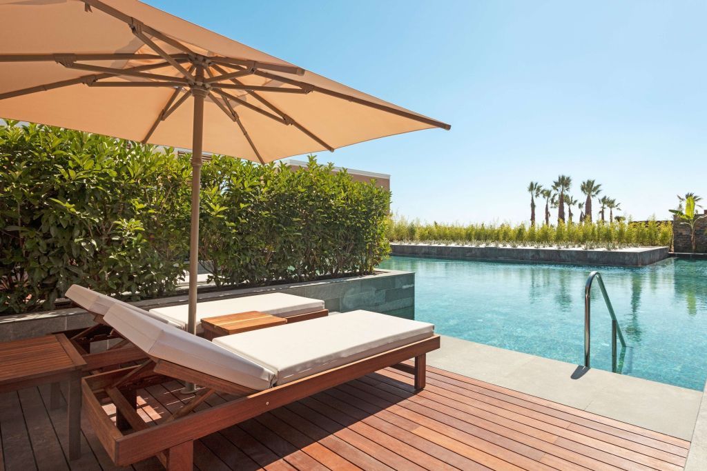 Private Terrasse mit Liegestühlen und Sonnenschirm am Pool.