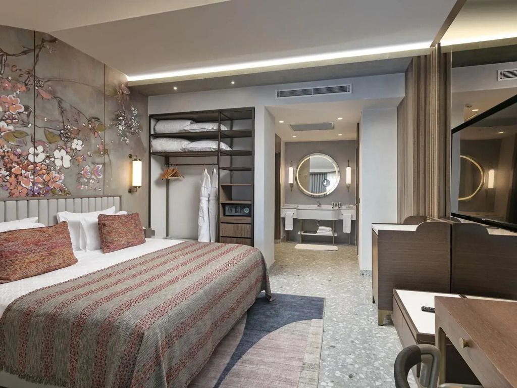 Komfortables Schlafzimmer mit Doppelbett und Blick ins Badezimmer mit Spiegel.