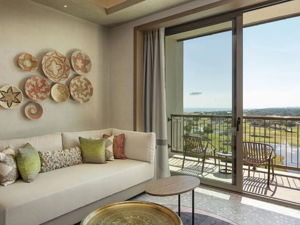 Wohnbereich mit Sofa und kunstvoller Wanddekoration, Balkon mit Meerblick