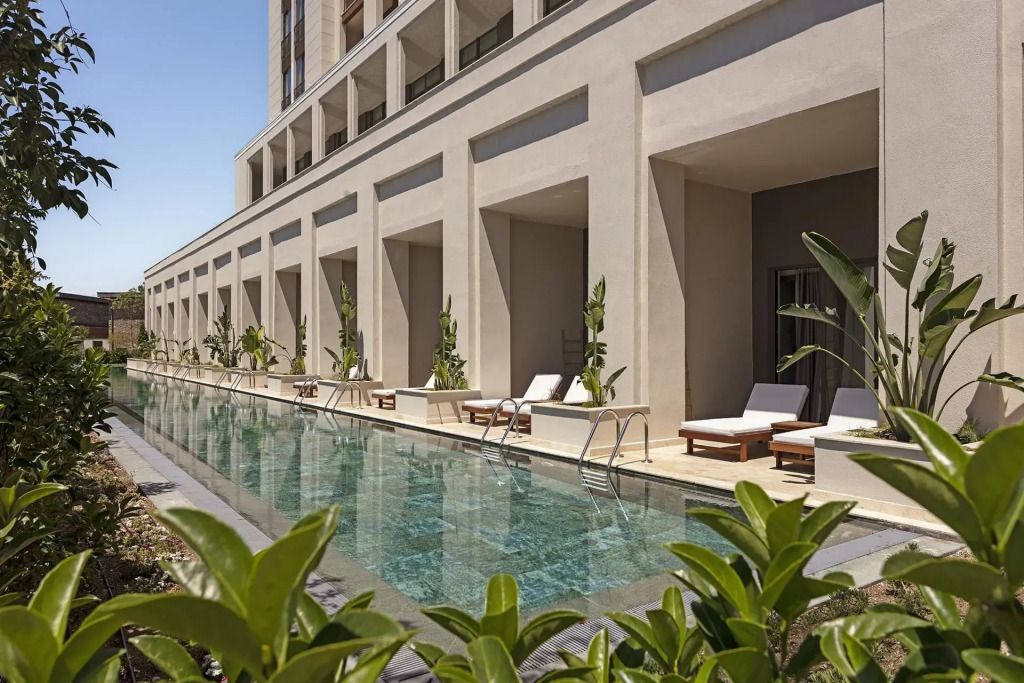 Außenbereich mit Pool und Sonnenliegen vor dem Gebäude