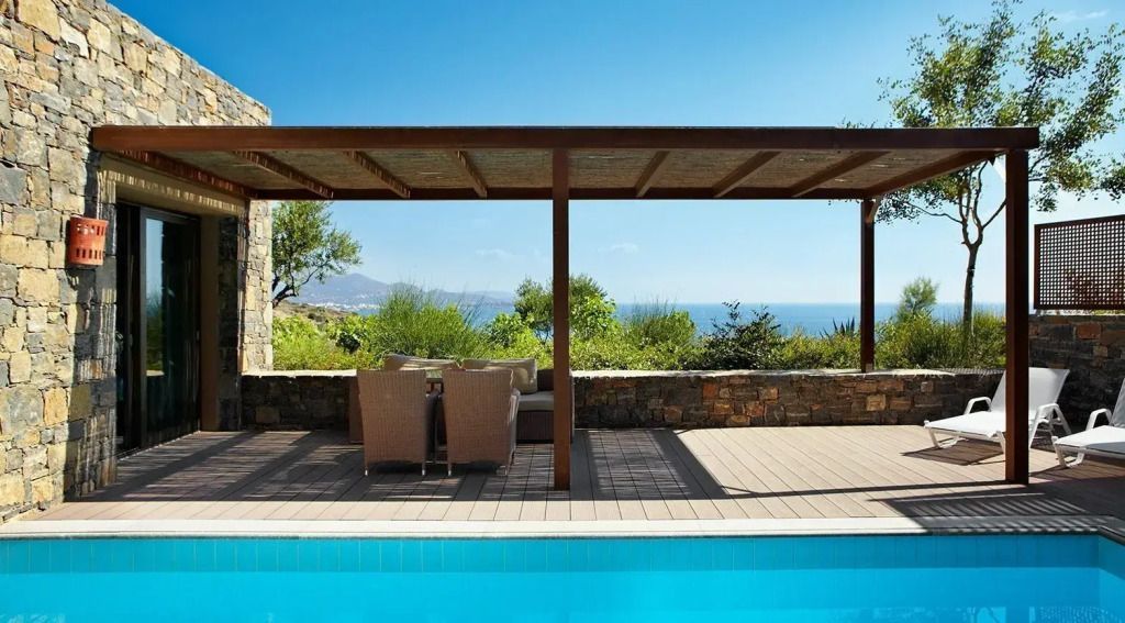 Terrasse mit Pool und möblierter Sitzecke vor Meereshintergrund
