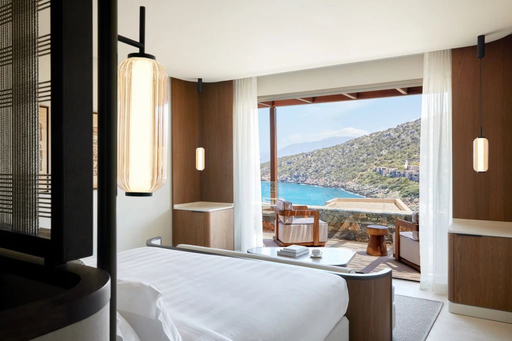 Schlafbereich mit Blick auf das blaue Meer durch große Fenster