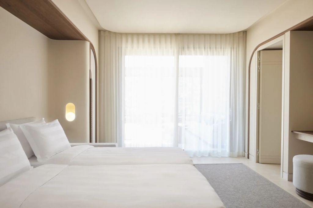 Helles Zimmer mit zwei Betten und Vorhängen aus weißem Stoff