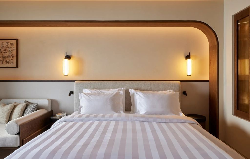 Elegantes Schlafzimmer mit modernen Wandlampen und gestreiftem Bettüberwurf