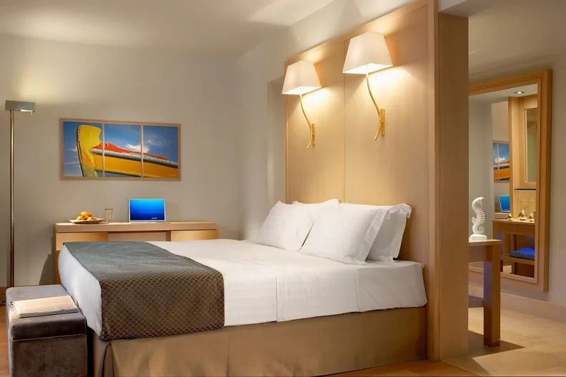 Gemütliches Schlafzimmer mit Doppelbett, Schreibtisch und stilvollen Wandleuchten.