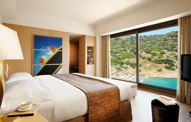 Modernes Schlafzimmer mit großem Bett und Aussicht auf die Bucht von großen Fenstern.