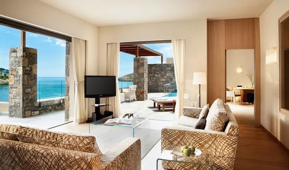 Helles Wohnzimmer mit Zugang zur Terrasse und Meerblick im Daios Cove Hotel