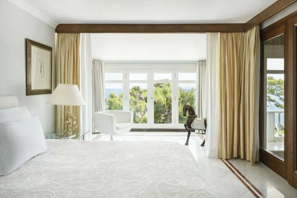 Geräumiges Schlafzimmer mit heller Dekoration und Fensterfront im Hotel The Danai