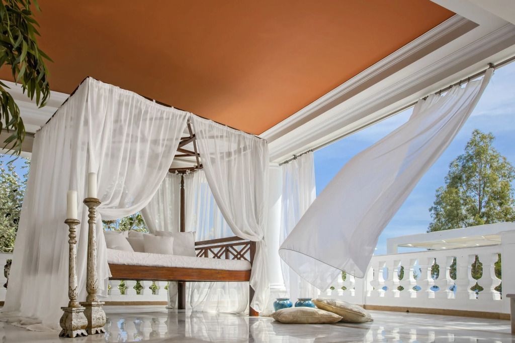 Luxuriöse Lounge mit Baldachin und wehendem Vorhang mit Meerblick