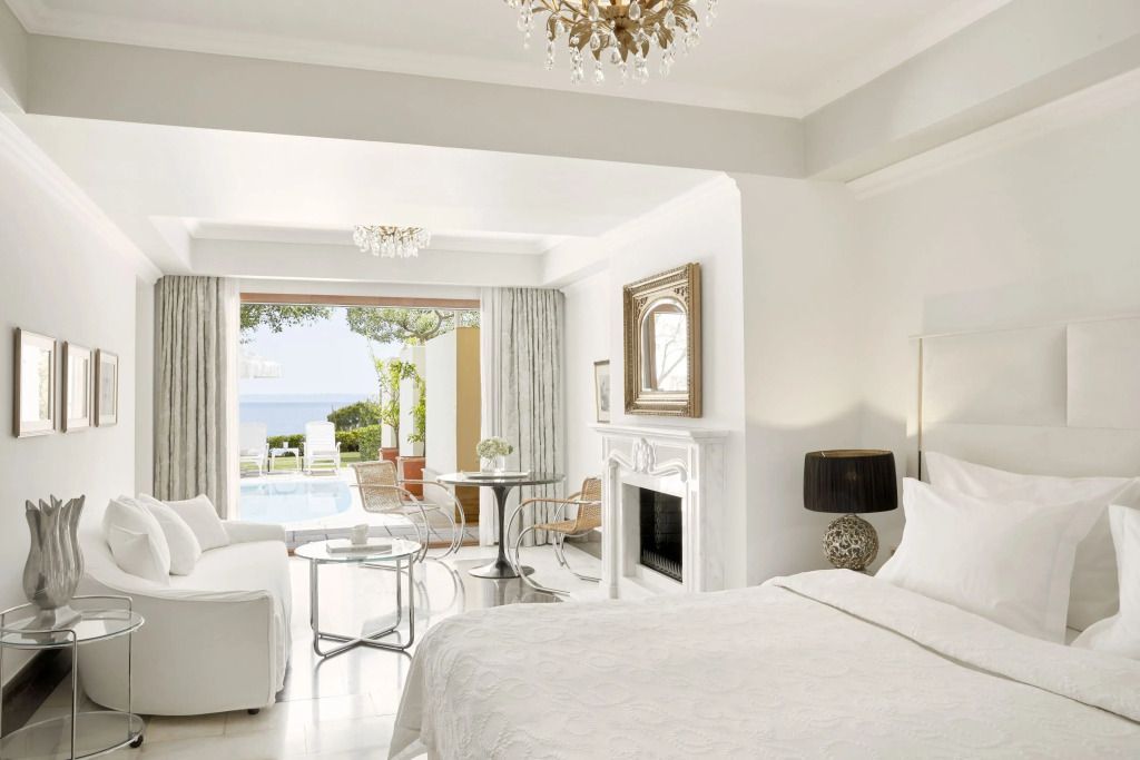 Helle Suite mit Blick auf einen privaten Pool und das Meer durch große Fenster.