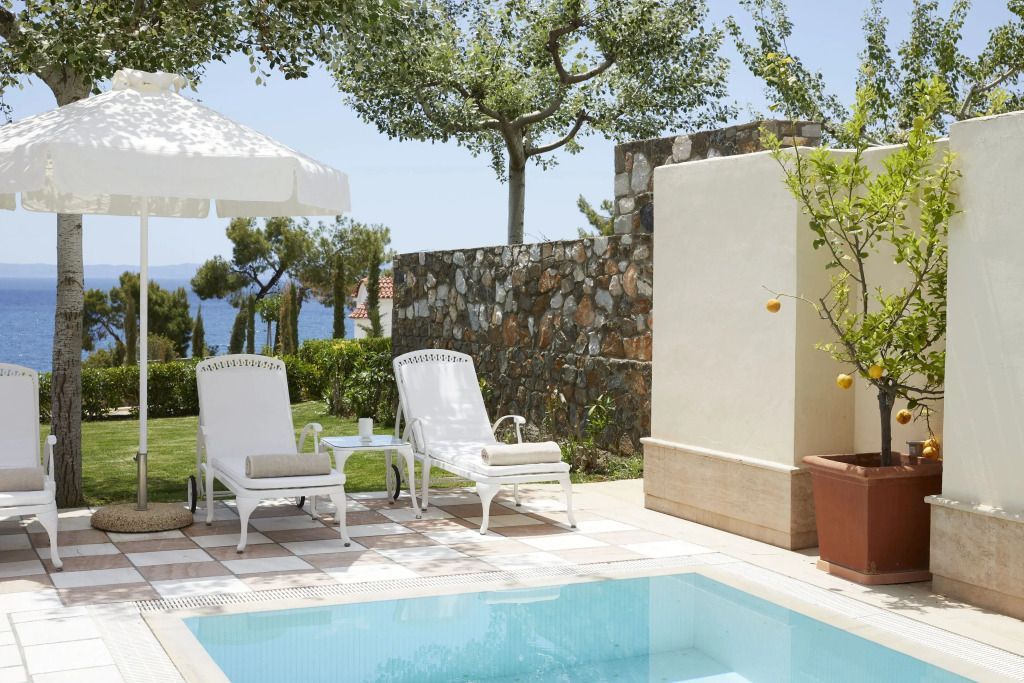Private Terrasse mit Pool und Liegestühlen und Blick auf das Meer.