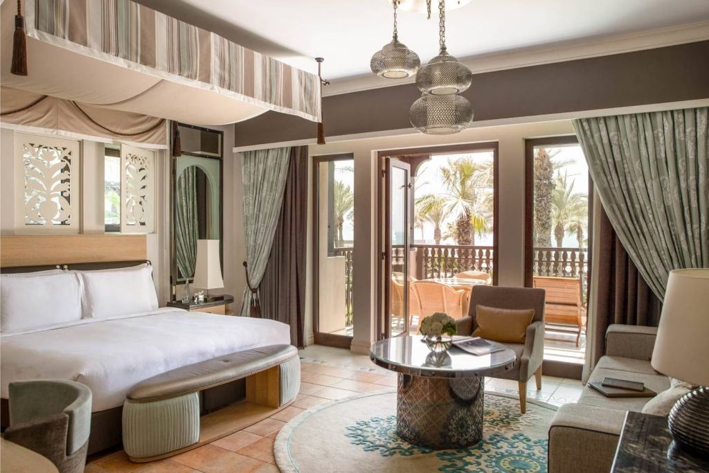 Luxuriöses Schlafzimmer in einem Beach House Cottage mit Blick auf den Balkon und Palmen.