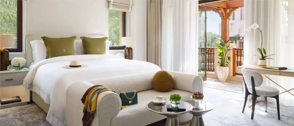 Luxuriöses Schlafzimmer mit elegantem Sofa und Blick auf Garten durch Balkonfenster.