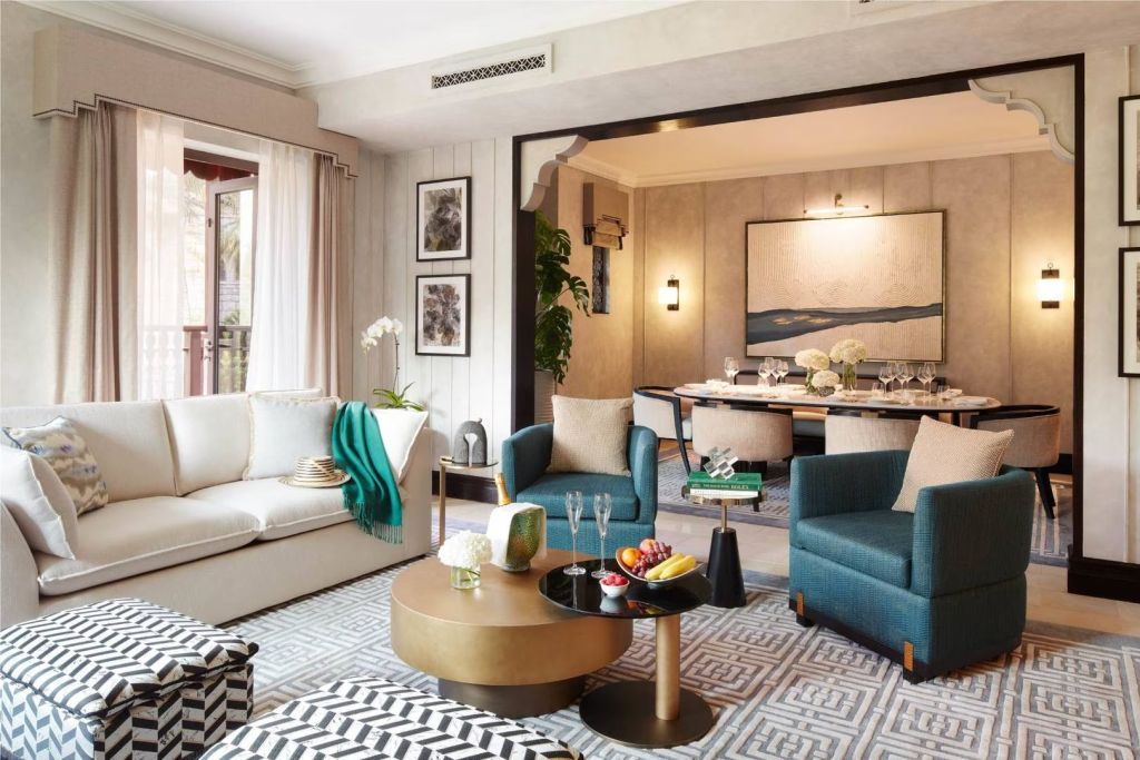Wohnzimmer der Suite mit stilvollem Sofa, Sesseln und Zugang zum Essbereich.