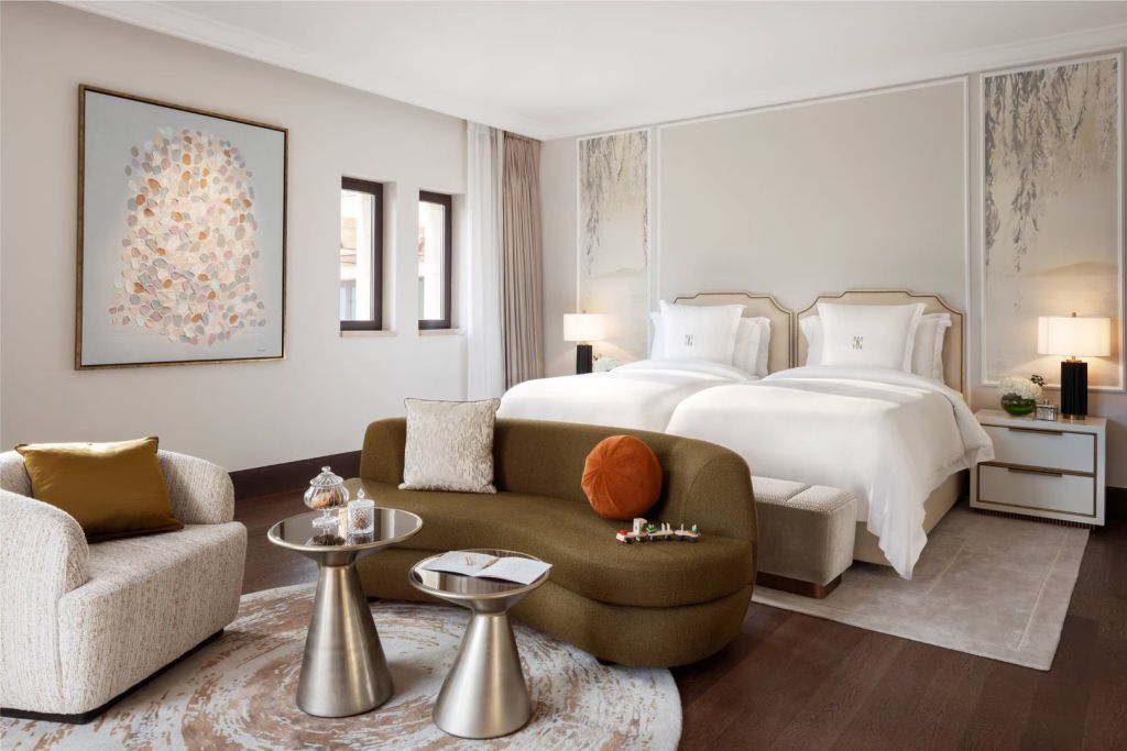 Geräumiges Schlafzimmer mit zwei eleganten Betten und moderner Kunst an der Wand