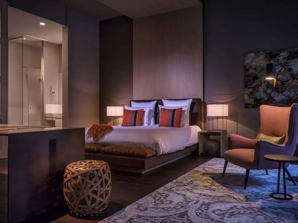 Elegante Suite mit Doppelbett, stimmungsvolle Beleuchtung und Kunstakzent