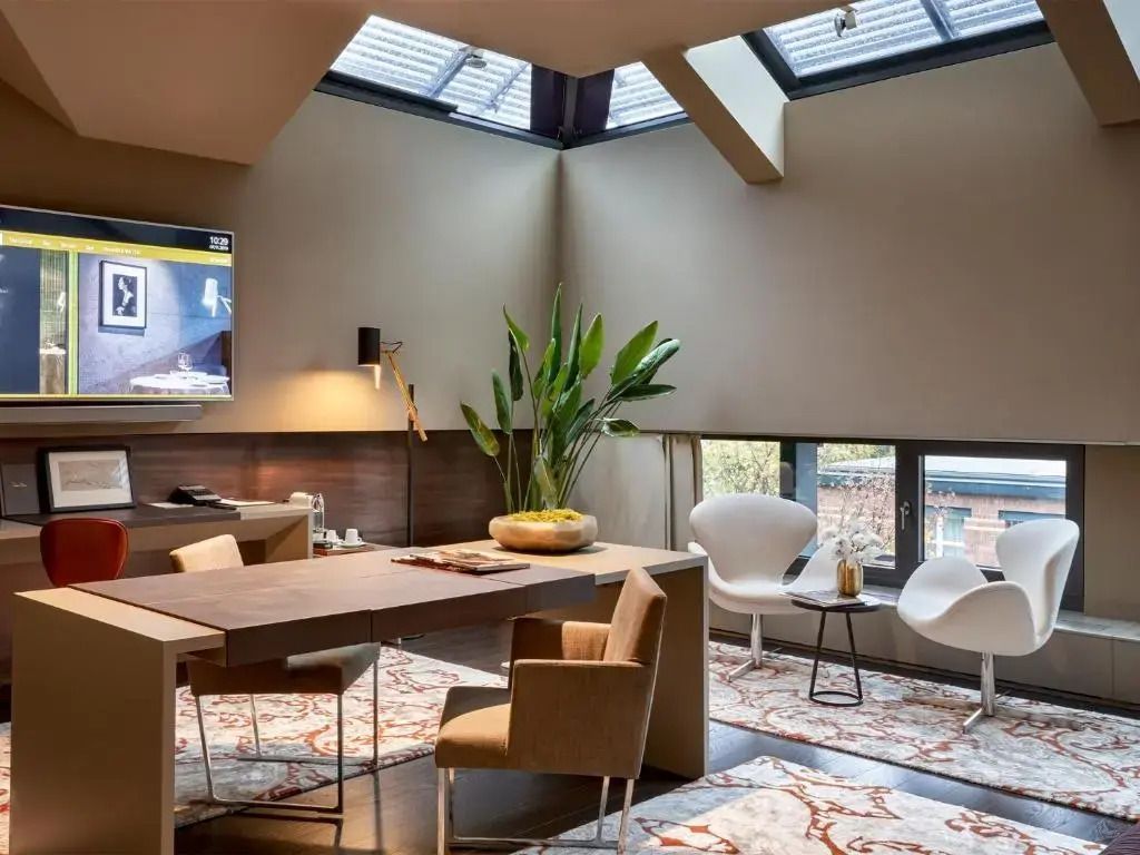 Raum mit Schreibtisch unter Dachfenster, Pflanzen und stilvollen Sitzgelegenheiten