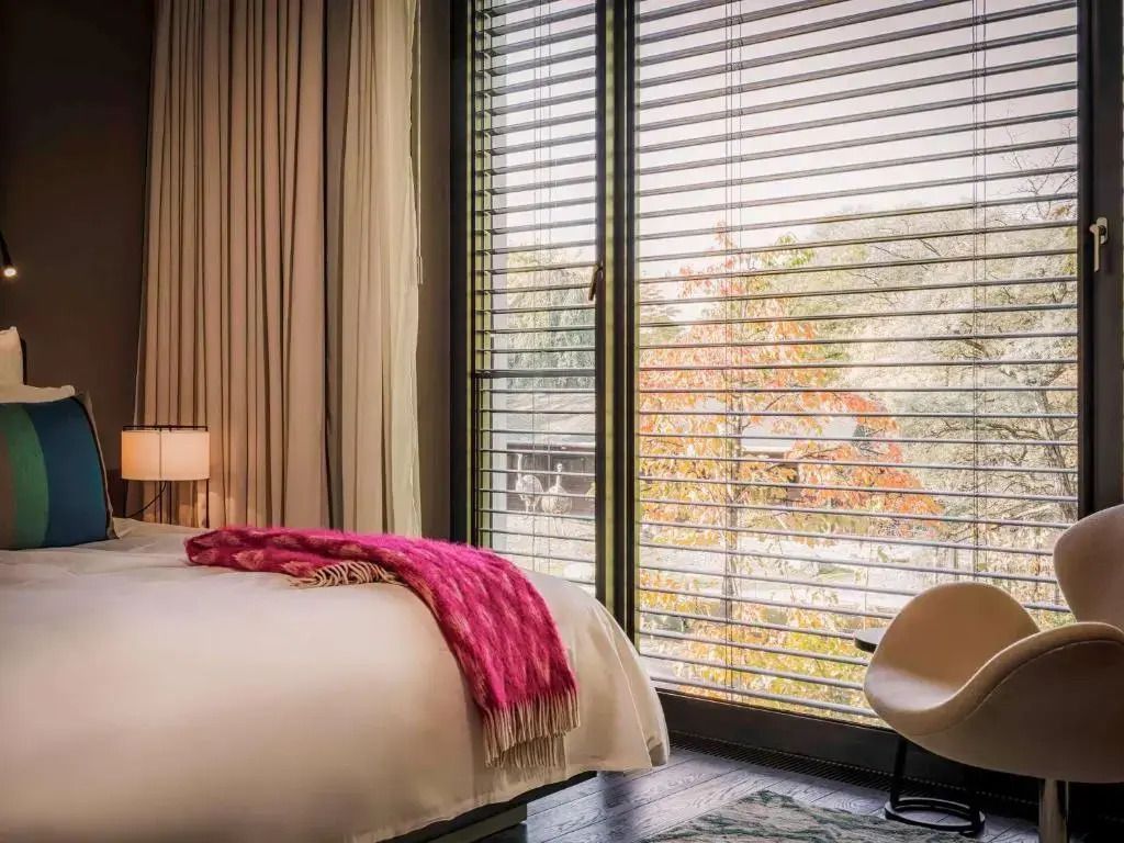 Helles Doppelzimmer mit großen Fenstern und Herbstlandschaft im Hintergrund